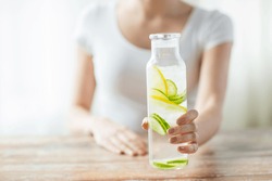 healthy eating, drinks, diet, detox and people concept - close up of woman with fruit infused water in glass bottle