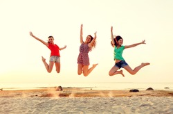 friendship, summer vacation, holidays, party and people concept - group of smiling teen girls jumping on beach