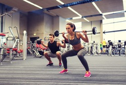 sport, bodybuilding, lifestyle and people concept - young man and woman with barbell flexing muscles and making shoulder press squat in gym