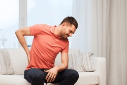 unhappy man suffering from backache at home
