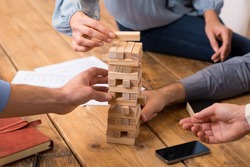 Close up of hands helping build a building of wooden pieces. Businesspeople planning a new business strategy. Business team trying to generate new ideas with wooden bricks. Business risk concept.
