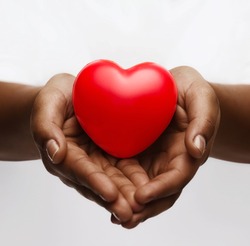 health, medicine and charity concept - close up of african american female hands with small red heart