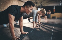 Fit young people doing pushups in a gym looking focused