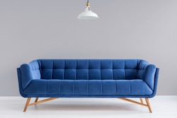 Grey interior with stylish upholstered blue sofa and lamp