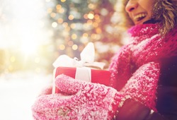 winter holidays, christmas and people concept - close up of happy woman with present or gift box outdoors