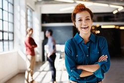 Portrait of a young businesswoman standing in an office with her colleagues in the background