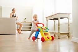 Portrait of an adorable baby girl playing with a toy walker at home