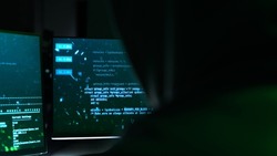 Back View of an Isolated Hacker Sitting In Front of the Computer With Hacking Codes Reflecting on Them. Hacking All the Databases, Planting a Virus into the Network. Hacker Concept.