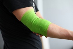 Man shows stretching on arm with elastic bandage. Bandage for people leading an active lifestyle, athletes as a prevention sprains and injuries. Elastic bandage on elbow joint with compression effect