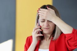 Woman is talking on phone and holding her forehead with her hand. Memory impairment forgetfulness concept