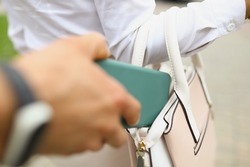 A man steals a wallet from a womans bag close up