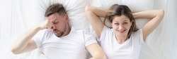 Married couple lying in bed. Man covering his nose with his hand. Increased gassing concept