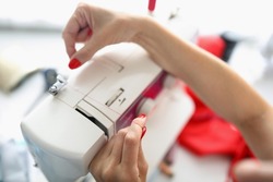 The dressmakers hands insert the thread into the sewing machine close-up. Care and operation of a modern sewing machine