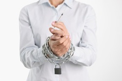 Drug addict is holding syringe with his hands tied by chain. Drug addiction concept