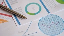 Close-up of metal pen on documents with colourful charts, graphs and diagrams. Planning business documents. Financial strategy calculation. Accountant analysis concept