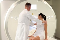 Portrait of doctor helping patient lie down for mri procedure. Patient at medical consultation. Magnetic resonance imaging and healthcare concept
