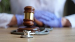 Close-up of judge gavel, doctor stethoscope and woman doctor on background. Medical malpractice, personal injury lawyer and healthcare legal aspects concept