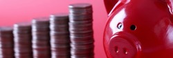 Coins in ascending order standing near red piggy bank closeup. Cash investment in business concept