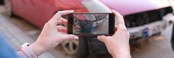 Woman holding smartphone and taking picture of car accident. Car insurance and payout concept