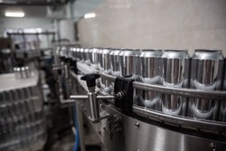 Technological line for bottling of beer in brewery. Empty aluminum beer cans are moving along the conveyor belt. Clean beer bottles are moving along the conveyor.Industry, production line, 