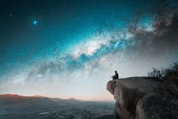 person sitting on the top of the mountain meditating or contemplating the starry night with Milky Way background	