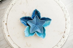 Ceramic blue sea stars decoration element of the home in apartment laying on the white vintage round table in living room. Interior decoration in nautical style  