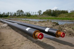 Construction of a district heating system for eco friendly homes.
The sustainable heat pipes for eco friendly houses in the Netherlands are photographed at a low angle with nature in the background.