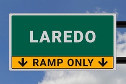 Laredo logo. Laredo lettering on a road sign. Signpost at entrance to Laredo, USA. Green pointer in American style. Road sign in the United States of America. Sky in background