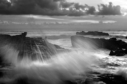 the water splash through the sea rock in mengening Rocky beach bali in black and white 