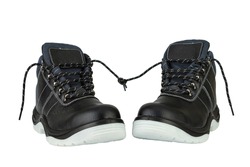 A pair of black leather work boots with thick gray soles on a white background. The ends of the laces are tied. The image is isolated. The boots are facing each other. Romantic date concept.
