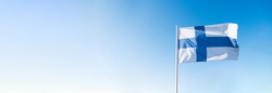 Finnish flag waving in wind and sunlight. Flag of Finland on blue sky background. Empty copy space for text. Finland independence day.