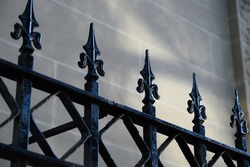 gothic iron gate with repeating pattern against a stone background