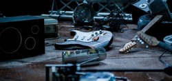 fragments of a broken guitar among the debris of the stage in the rain