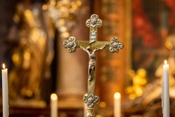 Golden Crucifix inside a baroque church or cathedral. Jesus Christ on a cross. Religion, belief, and hope. Holy and sacred places.