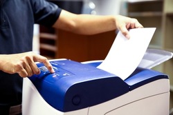 Technician hand press button and load paper in tray to using photocopier for scanning fax or photocopy or copy document after repairing paper jam or change toner cartridge in office workplace.