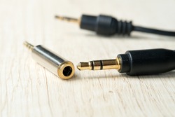 Plug 3.5mm Audio Jack to 2.5mm Audio Jack on a wooden workbench, a Modern technology concept. Selective focus