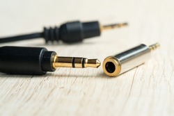 Plug 3.5mm Audio Jack to 2.5mm Audio Jack on a wooden workbench, a Modern technology concept. Selective focus
