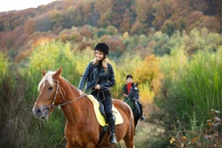 man and girl riding on separate  horses in mountains with amazing view. couple in love riding horses. professional jockeys. walk to remember on horses. couple equitation on black and brown horses. 
