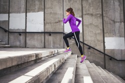 Slim attractive sports women running against a concrete wall