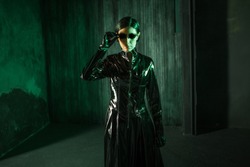 Girl hacker in the digital world. Young woman in matrix style suit. Black leather and sunglasses on black background