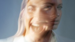 young stylish woman in a white jacket, distortions of the model's face on a long exposure. Second personality, alter ego concept
