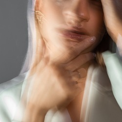 Fashion portrait with the effect of blurring in motion at a long shutter speed, distortion of the model's face. Young stylish woman in a white jacket