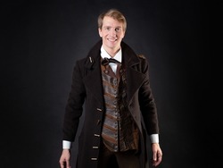 charming character of the steampunk story, a young attractive man in an elegant long coat. intelligent gentleman in the Victorian style. Vintage retro suit, young attractive man in a vest and bow tie