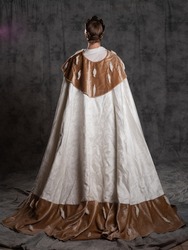 The young king. A noble young man in a fantasy historical costume, in a fur robe and with a crown on his head. The prince becomes the king, Full-length fur mantle back view
