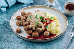 Swedish meatballs kottbullar, mashed potato, onion sauce and lingonberry sauce. Blue stone background. Selective focus