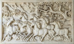 White wall sculpture depicting galloping horse.