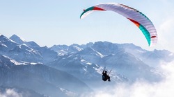 paraglider in the bernese alps.In the background mountain peaks of Eiger, Moench and Jungfrau, Switzerland

