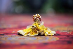 Lord Krishna also known as laddu gopal sculpture in beautiful clothes selective focus 