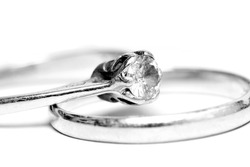 B&W diamond solitaire ring, resting on a wedding ring.