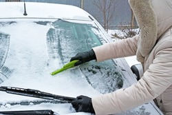 Winter car - woman remove snow and ice from windshield with snow scraper